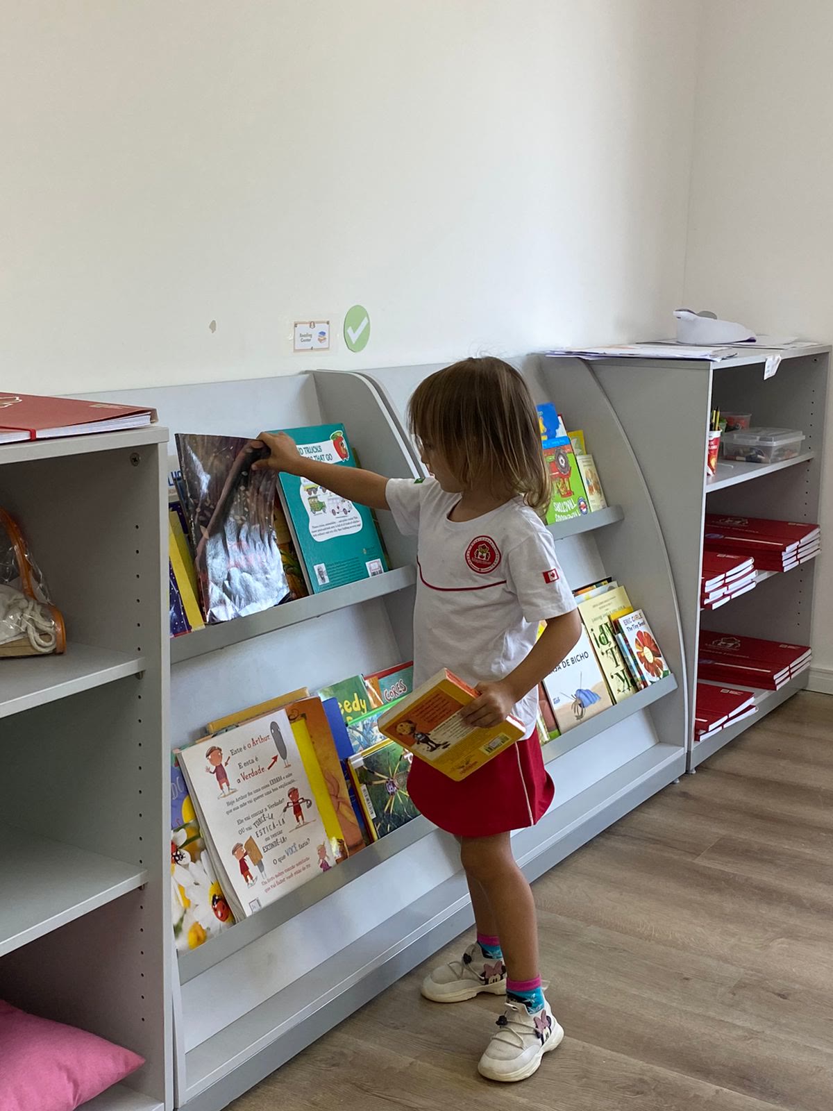 Criança escolhendo livro na biblioteca bilíngue da escola