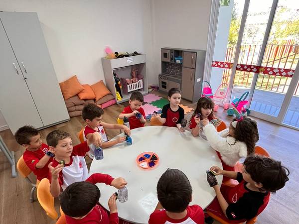 Crianças pequenas fazendo atividade em volta da mesa redonda