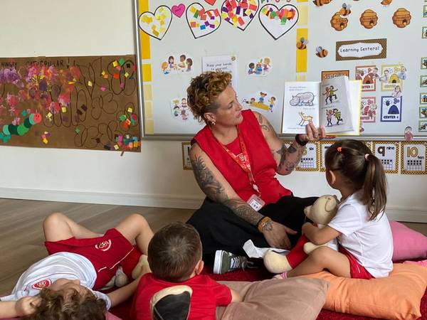 Professora conta uma história para as crianças sentadas no tapete