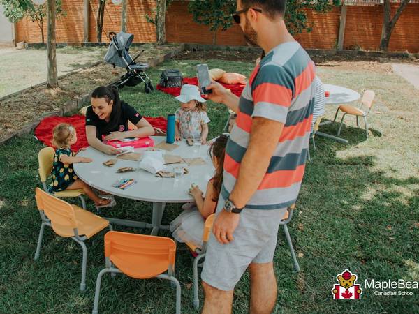 Famílias em piquenique com as crianças no gramado da escola