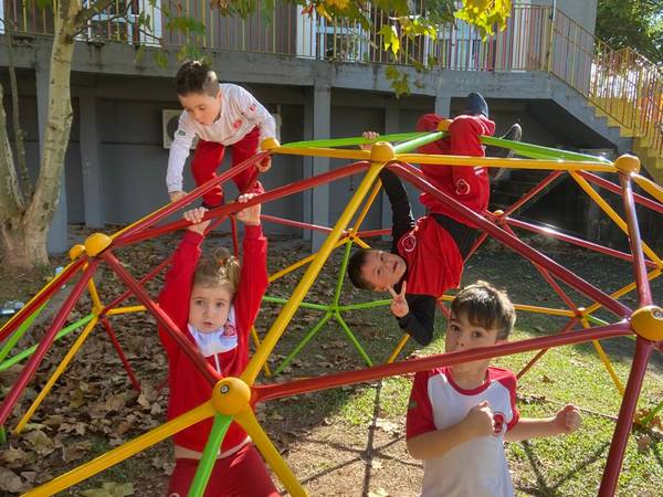Crianças brincando no trepa-trepa em forma de cúpula no pátio