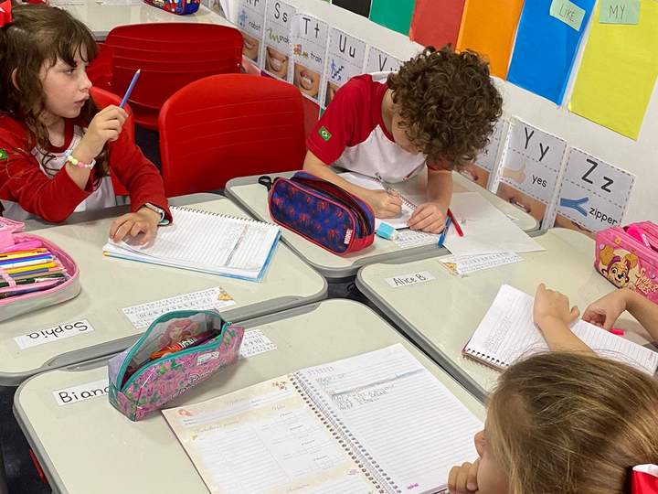 Crianças escrevendo em cadernos na sala de alfabetização da Maple Bear Caxias do Sul